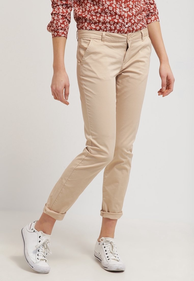 Beige chinos med slim fit och uppvikta fållar, matchade med vita sneakers. Slät bomullstyg med framfickor och klassisk midja.