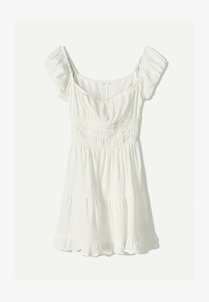 White, short-sleeved dress with a smocked bodice, tiered ruffle hem, and textured fabric. Features a wide, scooped neckline.
