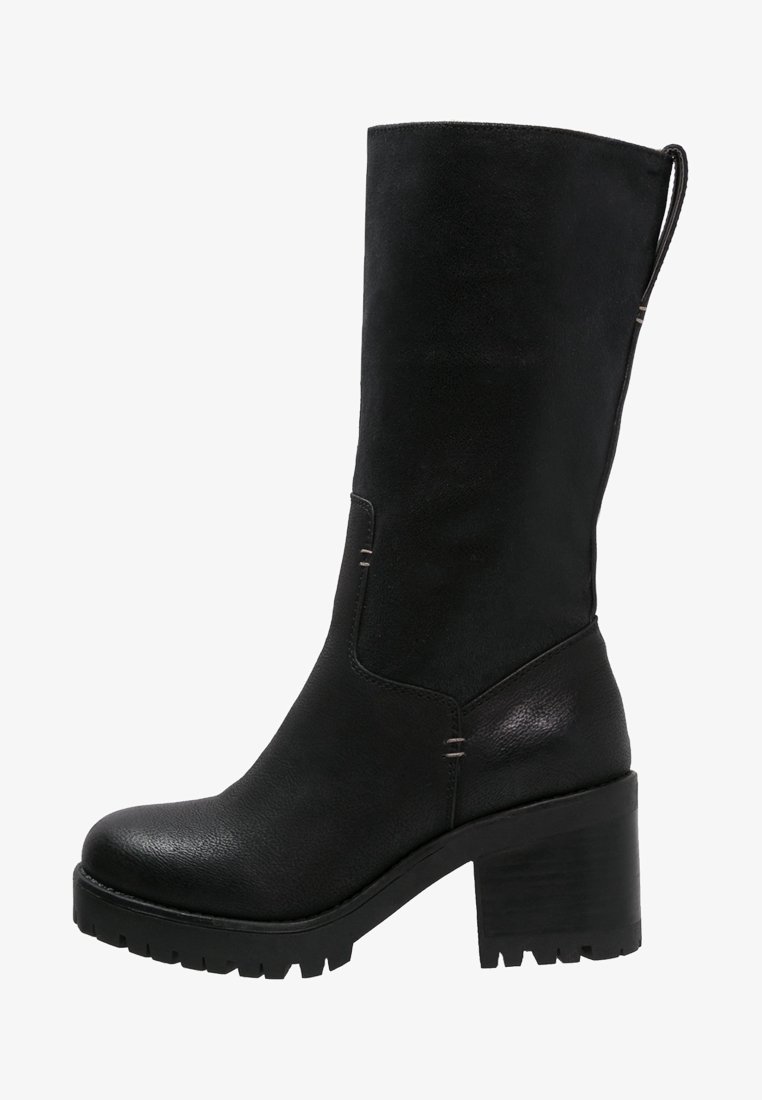 Bota negra hasta la rodilla con un tacón grueso, hecha de cuero texturizado. Presenta una punta lisa, costuras sutiles y una cinta en la parte superior para facilitar el uso.
