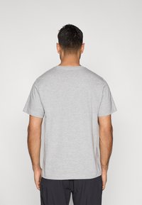 Γκρι βαμβακερό T-shirt με κοντά μανίκια και στρογγυλή λαιμόκοψη, εμφανίζεται από το πίσω μέρος. Απλός σχεδιασμός, χωρίς ορατά σχέδια ή διακοσμητικά.