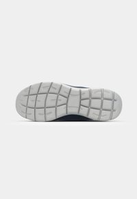 Shoe sole with a textured white rubber outsole featuring a grid pattern and raised tread for traction, set against a neutral background.
