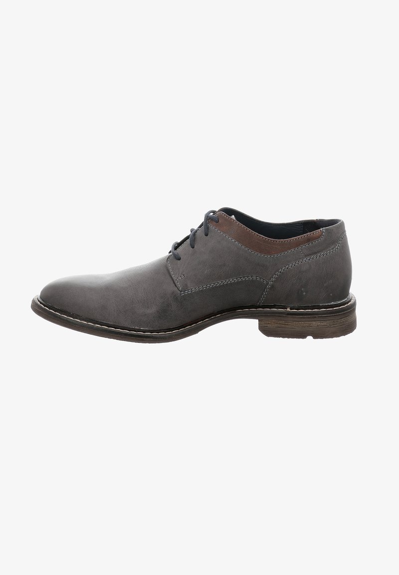 Chaussure en cuir gris avec une texture lisse, bout rond et subtils accents de couture. Lacets bleu marine et un détail en cuir marron en haut.