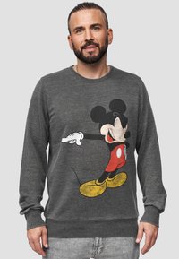 Grijze sweatshirt met een grote afbeelding van Mickey Mouse, met rode shorts, gele schoenen en witte handschoenen. Geribbelde manchetten en zoom.