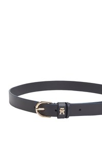 Ceinture en cuir noir avec une boucle en métal doré et un détail de logo. Texture lisse avec une forme arrondie et plusieurs trous pour l'ajustement.