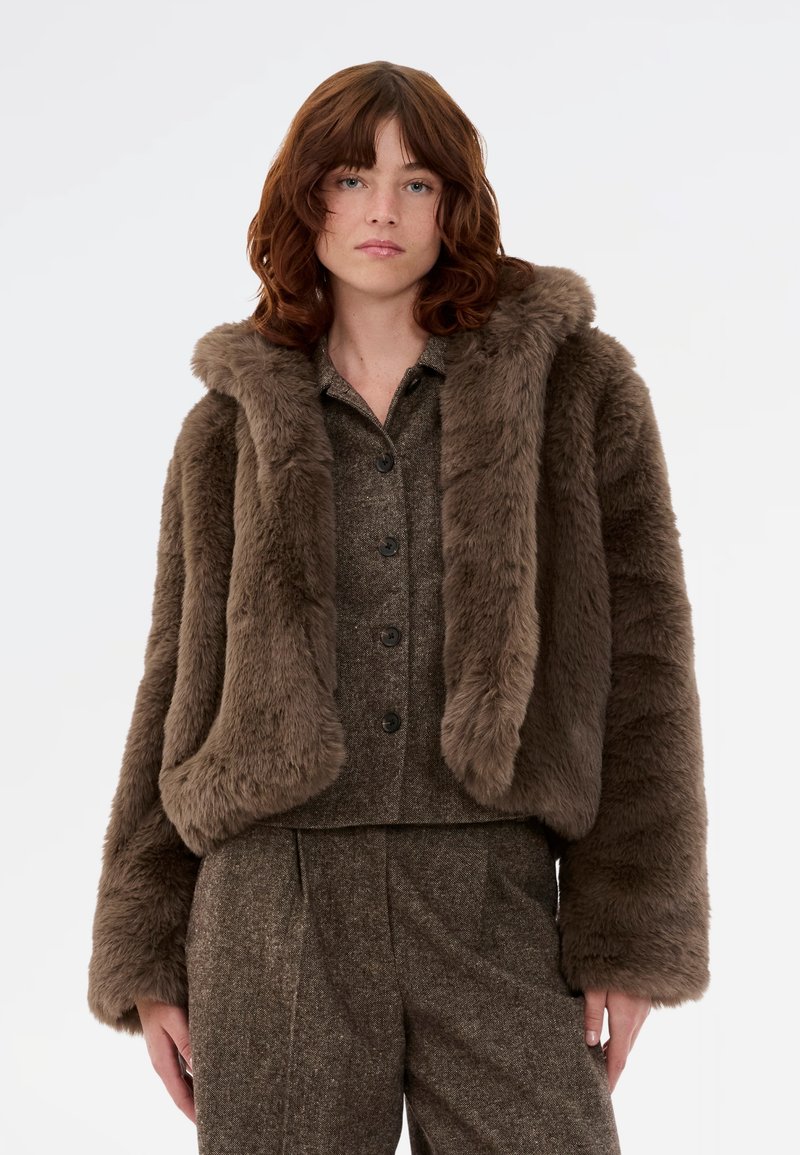 Rjava umetna krznena jakna s kapuco, ki se ponaša z mehkobo, širokimi rokavi in skrajšanim dizajnom. Preprost gumb za zapiranje spredaj.