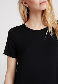 Czarny t-shirt z krótkim rękawem wykonany z miękkiego materiału, z klasycznym okrągłym dekoltem i luźnym krojem. Minimalistyczny design bez wzorów.