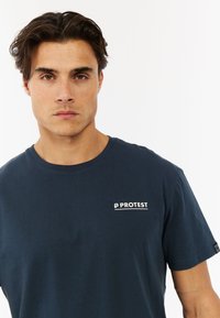 Navyblauwe T-shirt met korte mouwen, gemaakt van katoen, met een wit "PROTEST" logo op de linkerkant van de borst en een ronde hals.