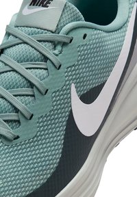 Scarpe sportive verde menta con tomaia in rete testurizzata, accenti di design ondulato, intersuola grigia e logo Nike swoosh bianco sul lato.