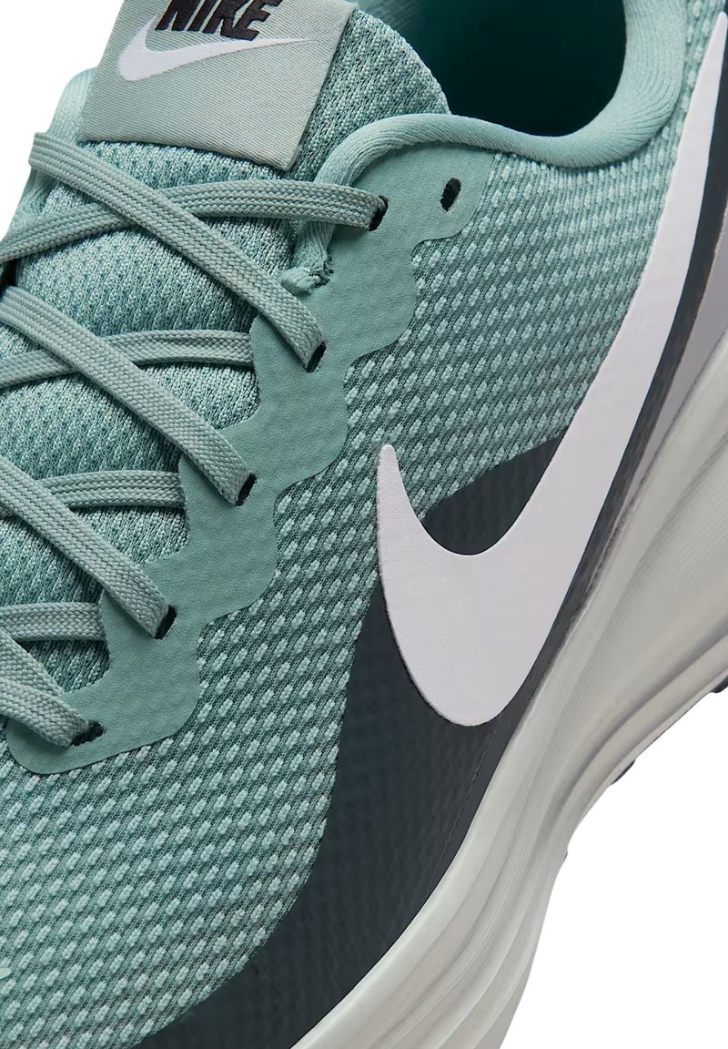 Baskets de sport vert menthe avec tige en mesh texturé, accents de design ondulés, semelle intermédiaire grise et logo Swoosh blanc de Nike sur le côté.