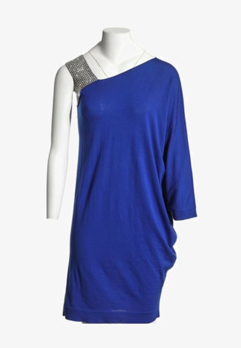 Robe bleue asymétrique avec une manche trois-quarts d'un côté et une bretelle cloutée argentée de l'autre, présentée sur un mannequin blanc.