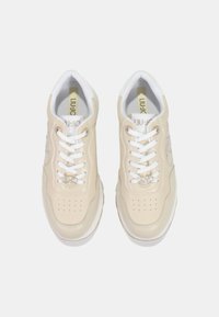 Sneaker in pelle beige con accenti bianchi, punta perforata e occhielli metallici. Presentano lacci bianchi e un logo sottile sul lato.