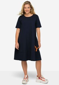 Navy t-shirt dress with short sleeves and a relaxed fit, featuring an orange logo on the side and a knee-length hem. Cotton-blend material.