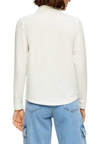 Lange mouwen blouse in off-white stof, met een klassieke kraag, een gladde textuur en een afgeronde zoom, gecombineerd met lichtblauwe jeans.