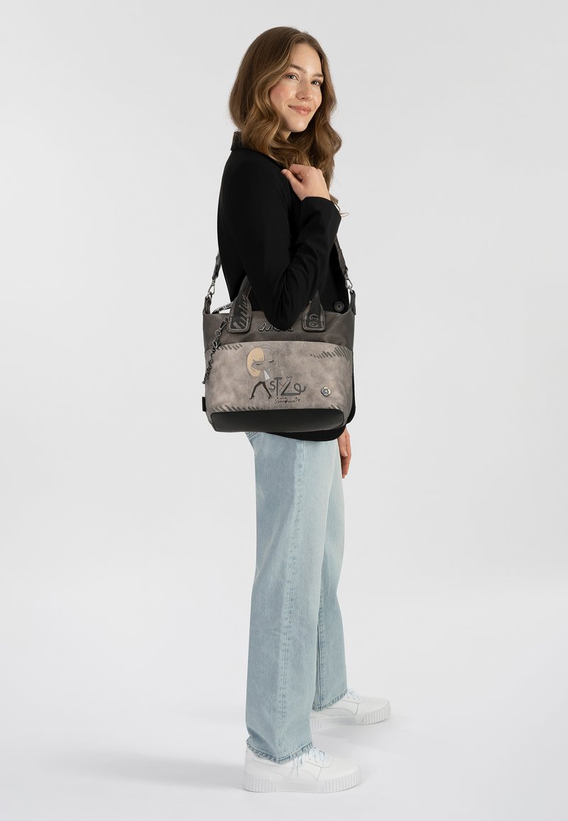 Bolso negro y gris con acentos de cadena, que presenta un diseño liso y texturizado. Detalles gráficos notables incluyen el nombre "ASTZ" y símbolos.
