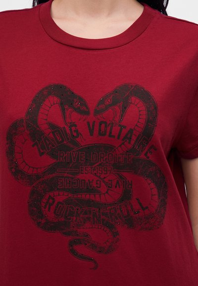 Κόκκινο T-shirt με μαύρο γραφικό δύο κεφαλών φιδιών που κοιτούν η μία την άλλη και κείμενο που γράφει Zadig Voltaire, Rive Droite, Rock N Roll.