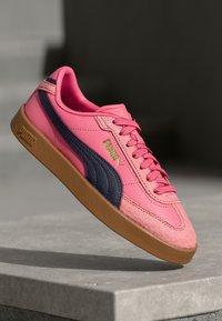 Rosa sneakers med marinblå rand, med överdel i mocka och syntetmaterial, gummisula och framträdande PUMA-logotyp i guld.