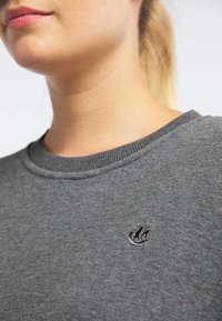 Grijze trui met een ronde hals, geribbelde manchetten en een klein geborduurd logo op de borst. Zachte textuur met een casual ontwerp.