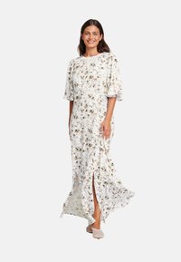 Blomstret maxi-kjole i lett stoff med korte flommelser, med hvit bakgrunn og brune blomster mønstre, sidespalter og en avslappet passform.