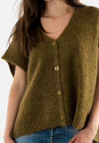 Chaleco de punto verde con escote en V, mangas cortas y cinco botones redondos. Hecho de un hilo suave y texturizado con un corte holgado.