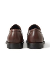 Braune Lederschuhe mit runden Zehen, glatter Textur, dekorativen Perforationen auf der Rückseite und schwarzen Gummisohlen.