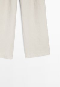 Lichtbeige broeken in een ontspannen, wijdbenig ontwerp. Gemaakt van een textuurstof met een ademende afwerking. Heeft schone, rechte zoomlijnen.