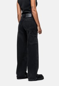 Jeans cargo neri a gamba larga in denim, con tasche laterali, vita alta e una texture liscia.