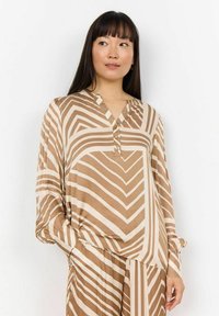 Langärmlige Bluse in Beige mit braunen Zickzackstreifen. Verfügt über einen V-Ausschnitt, Knöpfe am Kragen und einem locker sitzenden Design mit gerafften Ärmeln.