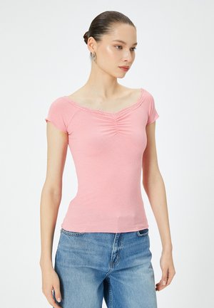 Top rosa a maniche corte con righe, colletto in pizzo e dettagli arricciati sul davanti, abbinato a jeans in denim blu.