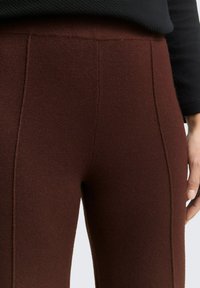 Bruine, gestructureerde legging heeft een aansluitend ontwerp met naden en is gemaakt van een rekbare, zachte stof voor comfort.