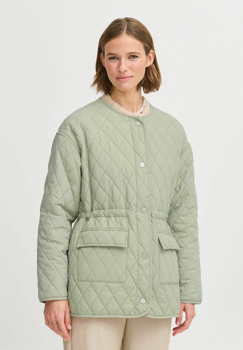 Chaqueta acolchada en verde claro, con cuello redondo, cierre de botones en el frente, dos bolsillos delanteros y una cintura elástica para un ajuste ceñido.