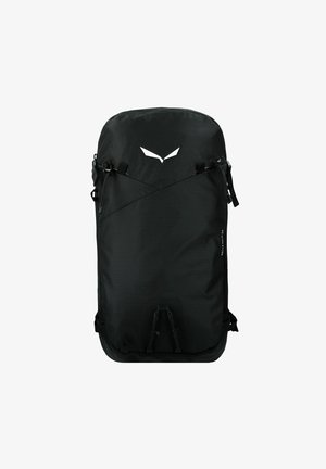 Mochila negra con textura suave, diseño minimalista y logotipo blanco. Cuenta con correas ajustables, asa superior y bolsillos laterales.