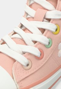 Ροζ πάνινο αθλητικό παπούτσι με λευκούς κορδόνια και πολύχρωμες τρύπες σε μπεζ, κοράλλι, πράσινο και κίτρινο.