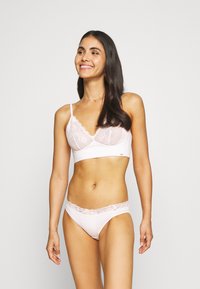 Bralette de renda rosa claro com uma faixa inferior suave e alças ajustáveis, combinado com cuecas biquíni com borda de renda correspondente. Costuras planas para conforto.