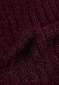 Tejido de punto burdeos con textura suave y peluda y patrón de canalé vertical. El material parece cálido y grueso, adecuado para prendas.