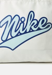 Pamut tote táska, nagy kék "Nike" logóval és világoskék swoosh-szal fehér háttéren. Simább textúra, téglalap alak.