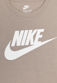 Sivá bavlnená tričko s veľkým bielym logom „NIKE“ a dizajnom swoosh na prednej strane, s rebrovaným okrúhlym výstrihom a mäkkou textúrou.