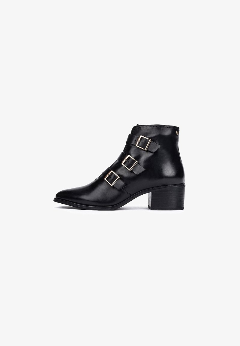 Botín de cuero negro con tres hebillas decorativas, punta afilada y tacón cuadrado. Textura suave con un acabado pulido.