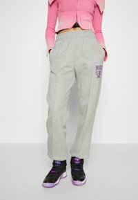 Grå joggingsbyxor med en lös passform, med ett elastiskt midjeband och en lila Nike-logotyp. Matchade med svarta och lila träningsskor.