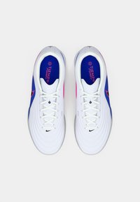 Λευκά αθλητικά παπούτσια με μπλε και ροζ λεπτομέρειες, υφή στην επάνω επιφάνεια, στρογγυλή μύτη και επίπεδη σόλα, με λευκά κορδόνια και λογότυπο της Nike στο πλάι.