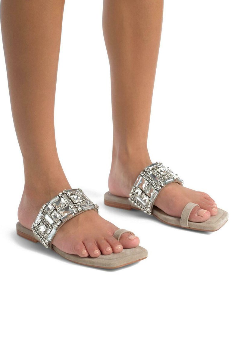 Sandali piatti beige con decorazioni in gemme d'argento, cinturini in suede e punte aperte, caratterizzati da un motivo geometrico sulla parte superiore.