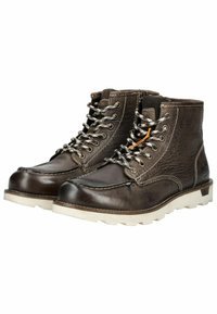 Bottes en cuir marron avec des détails texturés, semelles en caoutchouc blanches et lacets gris. Présente des accents et des coutures orange le long des bords.