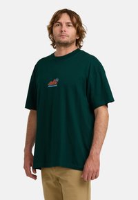 Camiseta de algodón de color verde oscuro con cuello redondo y mangas cortas. Presenta un diseño gráfico colorido en el pecho. Ajuste relajado y duradero.