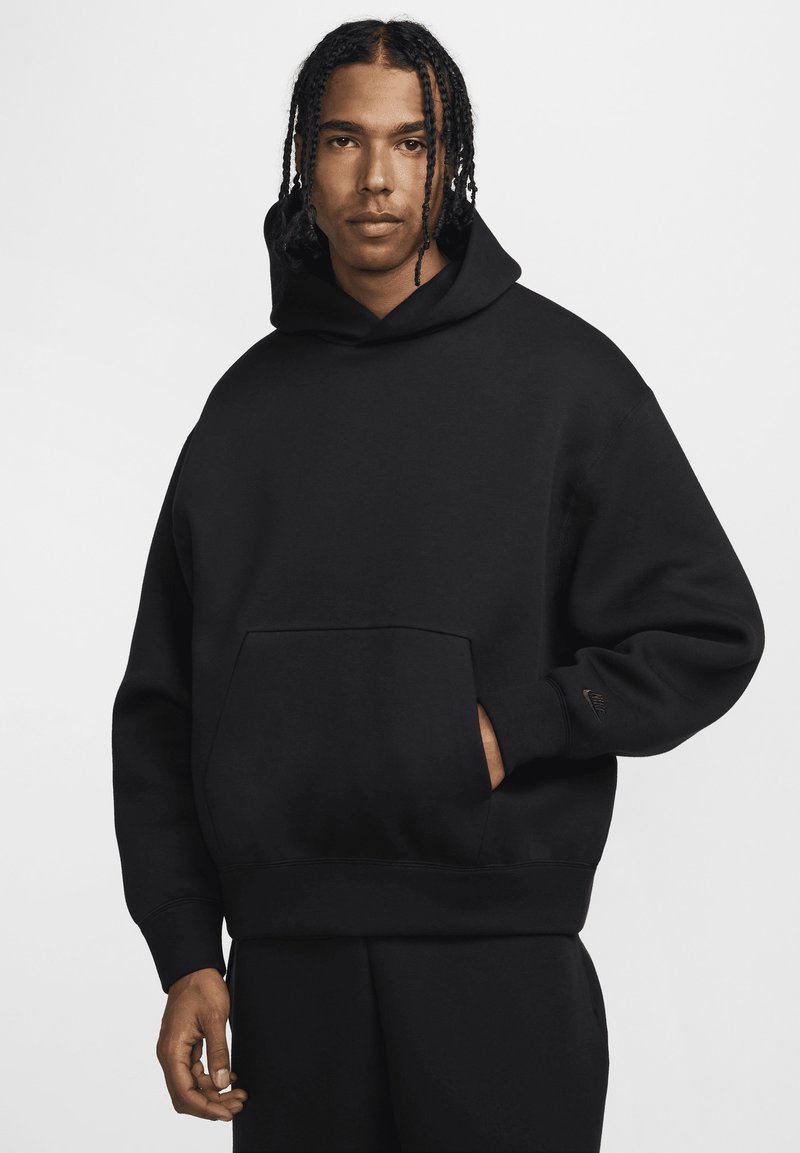 Sort hættetrøje lavet af blødt stof. Har en forlomme og Nike-logo på ærmet. Løs pasform med ribbede manchetter.