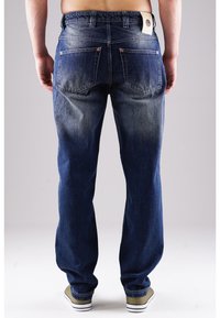 Dunkelblaue Denim-Jeans mit einem allmählichen Verblassen zu einem helleren Farbton. Gesäßtaschen mit Nähdetails und einem Etikett, das am Bund befestigt ist.