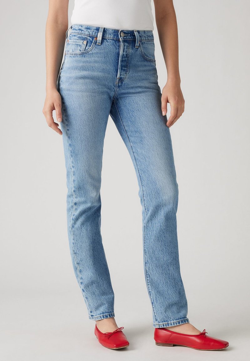 Lichtblauwe jeans met een klassieke rechte pasvorm, met een hoge taille, vijf zakken en subtiele wassing, gecombineerd met rode ballerina's.