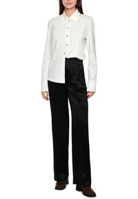 White long-sleeve button-up shirt with a classic collar and black buttons, paired with high-waisted black satin trousers and brown ankle boots.