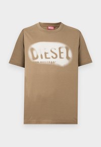 Καφέ βαμβακερό μπλουζάκι με το λογότυπο "DIESEL" σε λευκό, που μοιάζει να έχει ψεκαστεί με μπογιά. Κλασικό κόψιμο με στρογγυλή λαιμόκοψη και κοντά μανίκια, με λεία υφή.