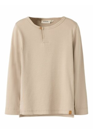 Beige geribd kindertruitje met lange mouwen, ronde hals en een houten knoopje bij de hals.