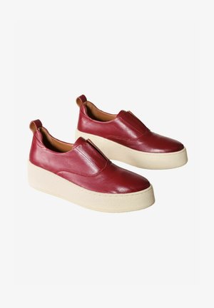 Czerwone skórzane buty wsuwane z zaokrąglonym noskiem i grubą kremową podeszwą. Akcentowane małą pętelką z tyłu.