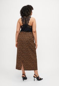 Svart blonde tanktop med lav rygg, kombinert med et leopardmønstret, knelangt skjørt med en frontsliss. Svart høye hæler.